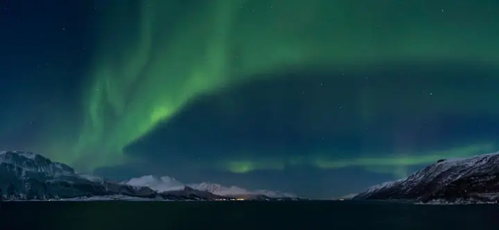 The aurora borealis over snow capped mountains