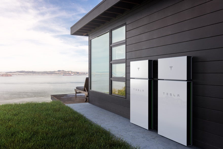 Two Tesla Powerwall batteries mounted on the exterior wall of a home