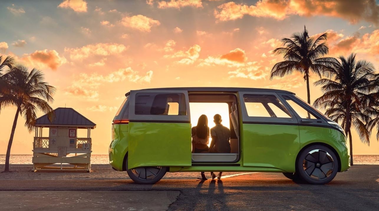 Couple sitting in a green Volkswagen ID.4 parked on a beach